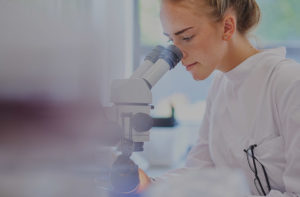 Pharmaceutical researcher looking into a microscope
